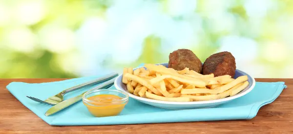 Batatas fritas com hambúrgueres no prato em fundo verde close-up — Fotografia de Stock