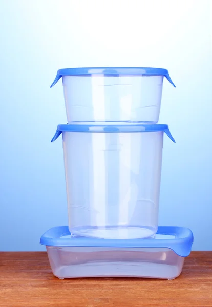 Пластиковые контейнеры для еды на деревянном столе на синем фоне — стоковое фото