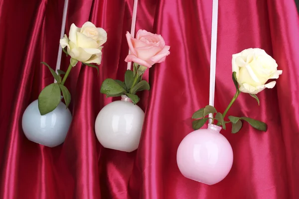Mooie rozen in vazen opknoping op doek achtergrond — Stockfoto