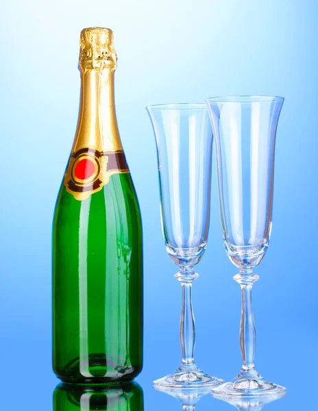 Láhev šampaňského a pohárů na modrém pozadí — Stock fotografie