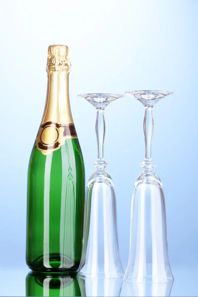 Garrafa de champanhe e taças sobre fundo azul — Fotografia de Stock