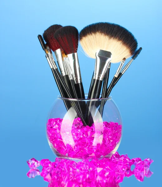 Make-up-Pinsel in einer Schüssel mit Steinen auf blauem Hintergrund — Stockfoto
