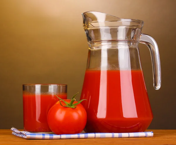 Tomatensap in werper en glas op houten tafel op bruine achtergrond — Stockfoto