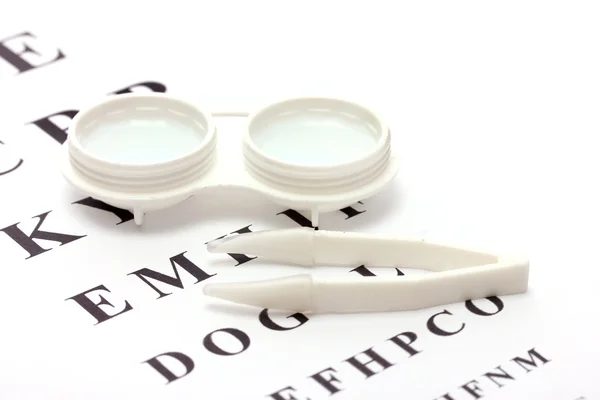 Kontaktlinser i behållare och pincetter, på snellen öga diagram bakgrund — Stockfoto