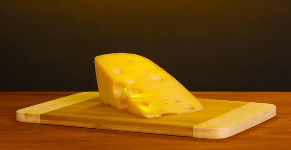 Stock image Cheese on cutting board on wooden table on brown background