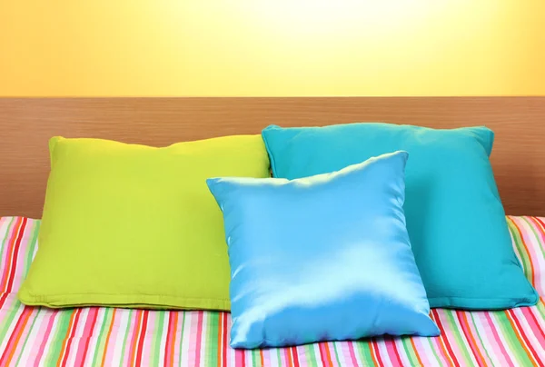 黄色の背景にベッドの上の明るい枕 — ストック写真