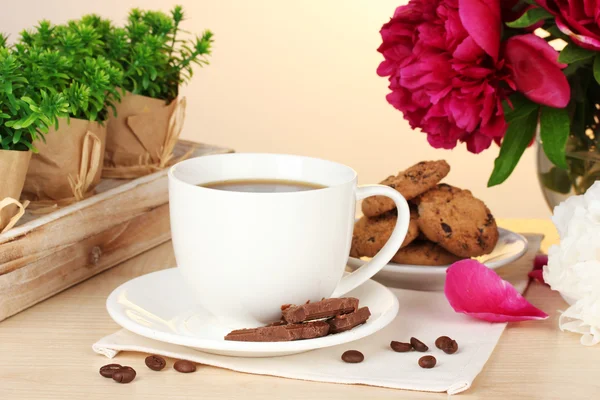 Tazza di caffè, biscotti, cioccolato e fiori sul tavolo nel caffè — Foto Stock
