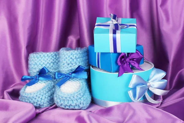 Blue baby boots and gifts on silk background — Stock Photo, Image