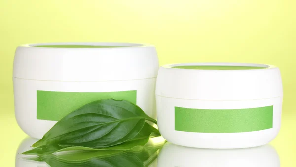Vasi di crema con foglie verdi su sfondo verde — Foto Stock