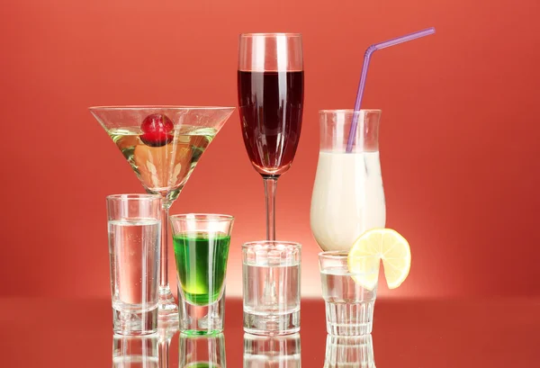 赤い背景の上のアルコール飲料のさまざまな — ストック写真