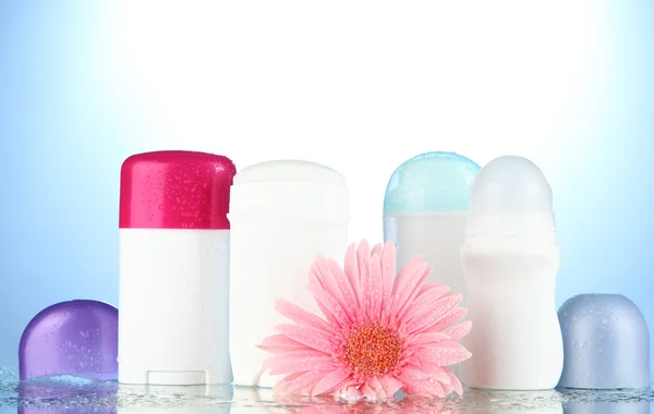 Deodorant botttles met bloem op blauwe achtergrond — Stockfoto