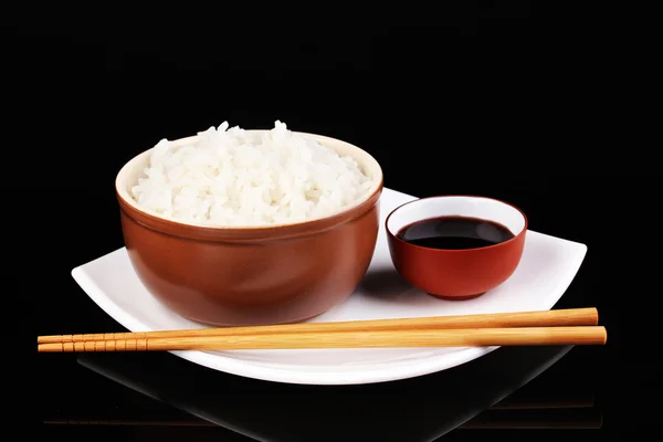 Ciotola di riso e bacchette su piatto isolato su nero — Foto Stock