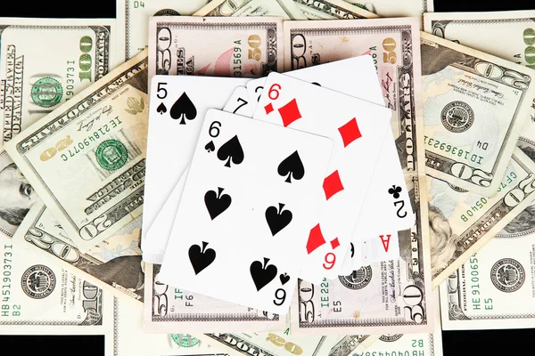 Dólares e um baralho de cartas de baralho em fundo preto close-up — Fotografia de Stock