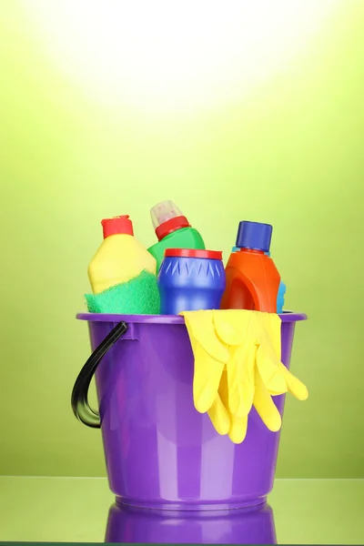 Bucket with cleaning items on green background — Stock Photo, Image