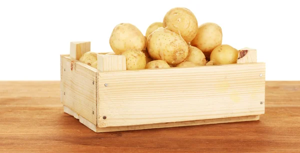 Unge kartofler i en trækasse på et bord på hvid baggrund close-up - Stock-foto