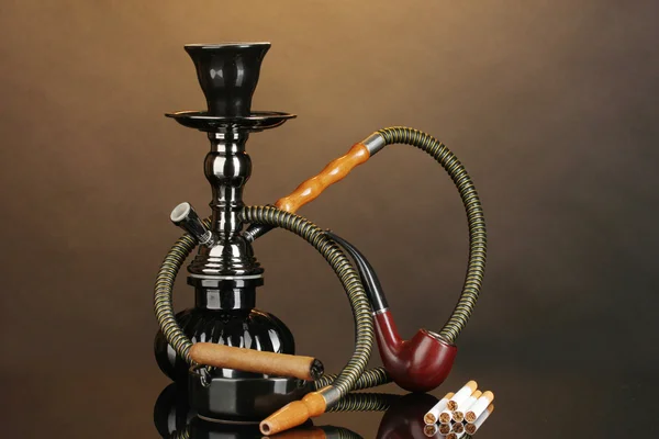 Ferramentas de fumagem - um narguilé, charuto, cigarro e tubo em fundo marrom — Fotografia de Stock