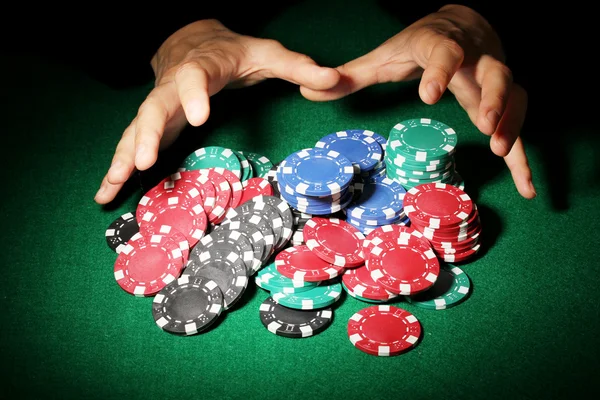 Poker žetony a ruce nad ní na zeleném stole — Stock fotografie