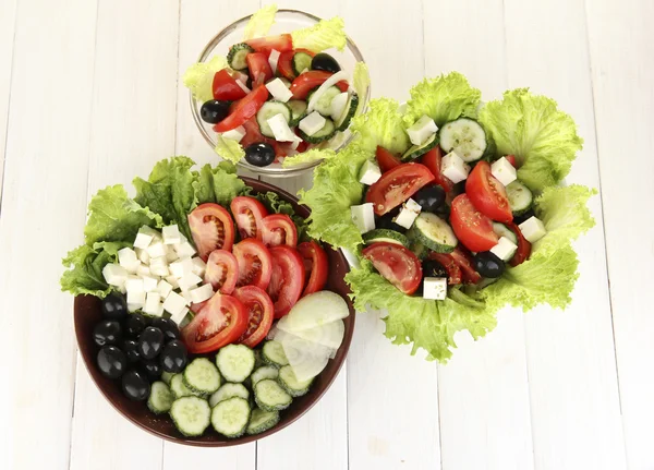 Drei leckere griechische Salate auf weißem Holzhintergrund — Stockfoto