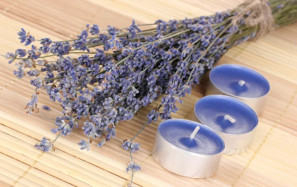 Lavender flowers with candles on bamboo mat — Stock Photo, Image