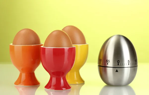 Temporizador de ovo e ovo em suporte de cor no fundo verde — Fotografia de Stock