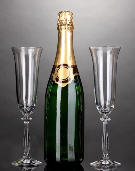 Bir şişe şampanya ve gri arka plan üzerinde kadehler — Stok fotoğraf