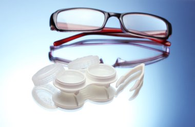 Glasses, contact lenses in containers and tweezers on blue background clipart