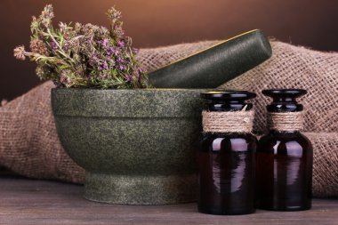 Thyme herb and mortar on wooden table on brown background clipart