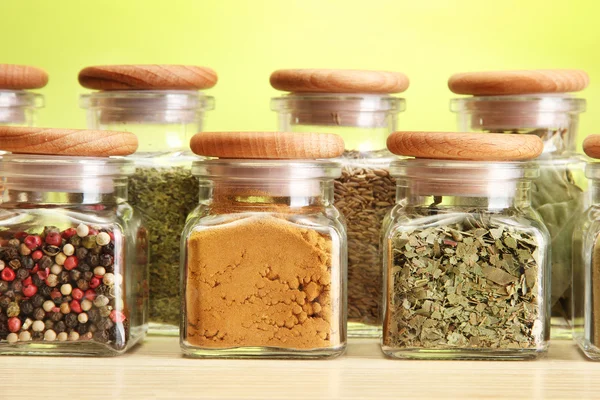 Pulver kryddor i glasburkar på grön bakgrund — Stockfoto