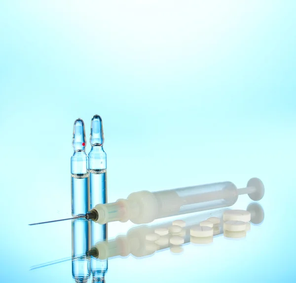 Syringe monovet, ampoules and pills on blue background — Stock Photo, Image