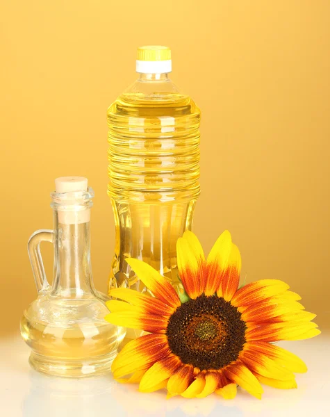 Zonnebloemolie in een plastic fles en kleine karaf op gele achtergrond — Stockfoto