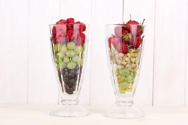 Frutas y bayas mixtas en vasos sobre fondo de madera — Foto de Stock