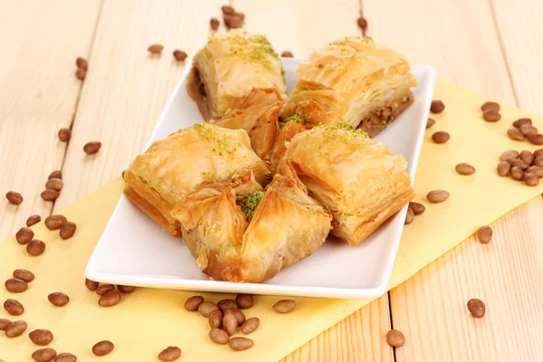 Zoete baklava op plaat op houten achtergrond — Stockfoto