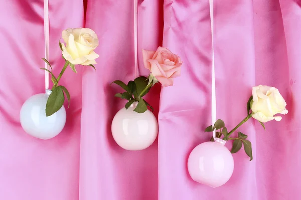 Schöne Rosen in Vasen hängen auf Stoffhintergrund — Stockfoto