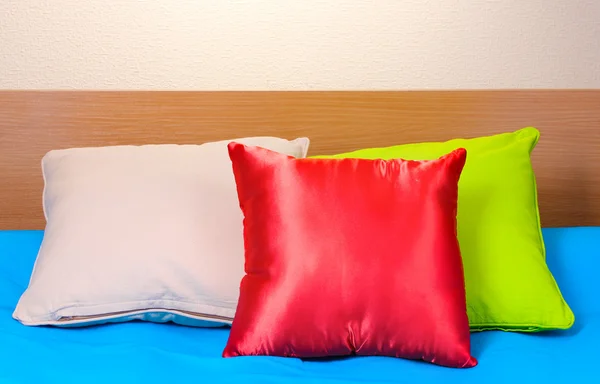 Světlé polštáře na posteli na béžové pozadí — Stock fotografie