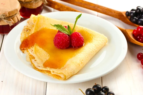 Leckere Pfannkuchen mit Beeren und Honig auf Teller auf Holztisch — Stockfoto