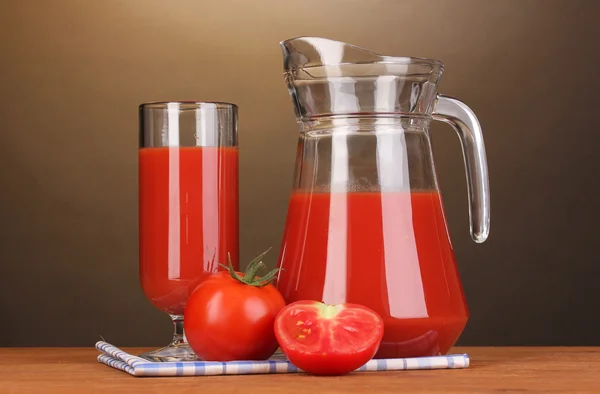 Jugo de tomate en jarra y vaso sobre mesa de madera sobre fondo marrón — Foto de Stock