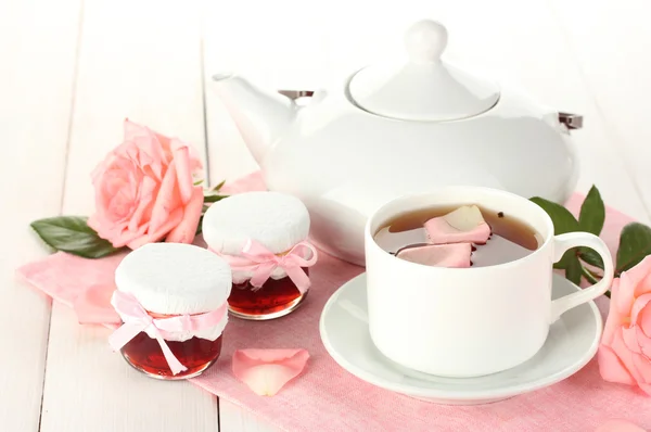 Teapot and cup of tea with roses and jam on white wooden table — Stock Photo, Image