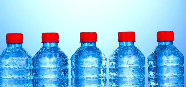 Bottiglie di plastica di acqua su sfondo blu — Foto Stock