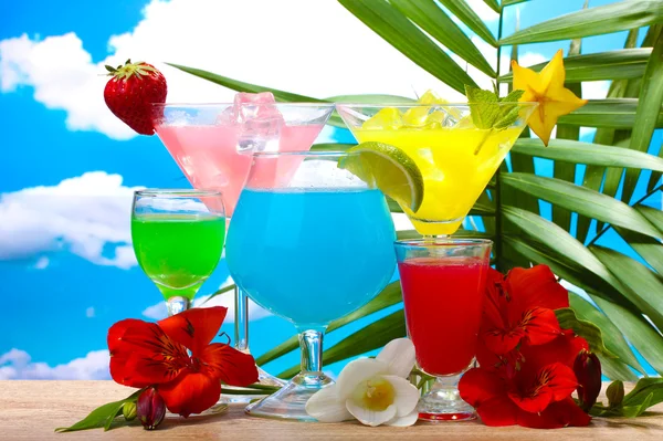 Exotiska drinkar och blommor på bordet på blå himmel bakgrund — Stockfoto