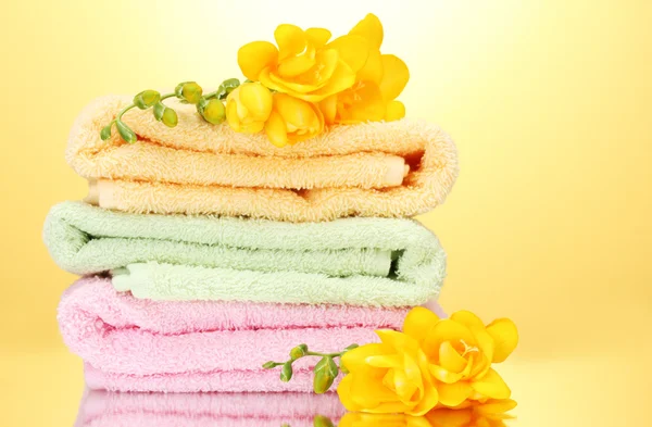 Красочные полотенца и цветы на желтом фоне — стоковое фото
