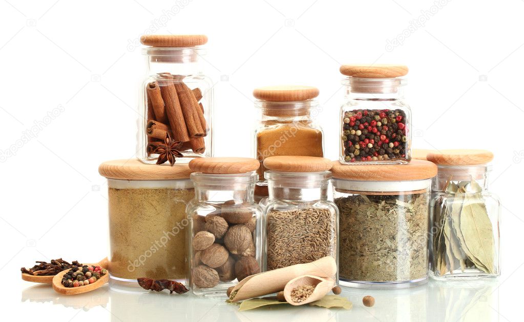 Jars and wooden spoons with spices isolated on white