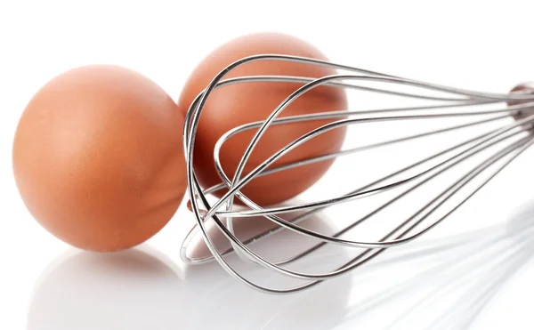 Batidor de metal para huevos batidos y huevos marrones aislados en blanco — Foto de Stock