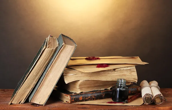 Stare książki, przewija, atrament pióro i Kałamarz na drewnianym stole na brązowym tle — Zdjęcie stockowe