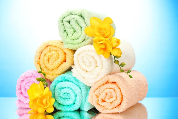 Colorful towels and flowers on blue background — Stock Photo, Image