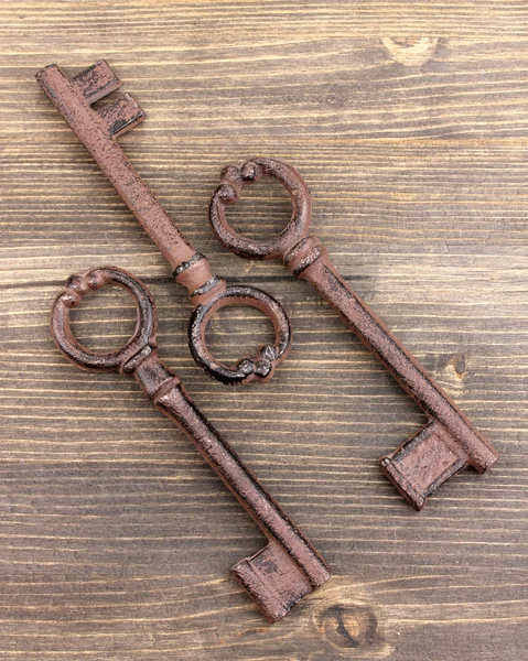 Three antique keys on wooden background — Stock Photo, Image