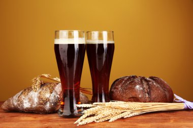 Two glasses of kvass with bread on brown background close-up clipart