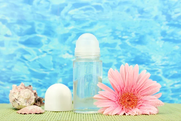 Deodorant, flower and shells on blue sea background — Stock Photo, Image