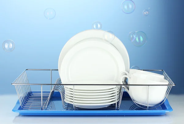 Чистий посуд на підставці на синьому фоні — стокове фото