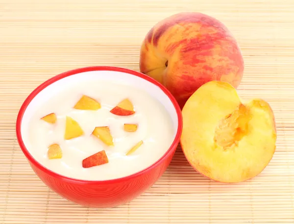 Йогурт з персиком в мисці на бамбуковому килимку — стокове фото