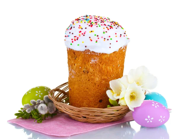 Bella torta di Pasqua in cesto, uova colorate e fiori isolati su bianco — Foto Stock